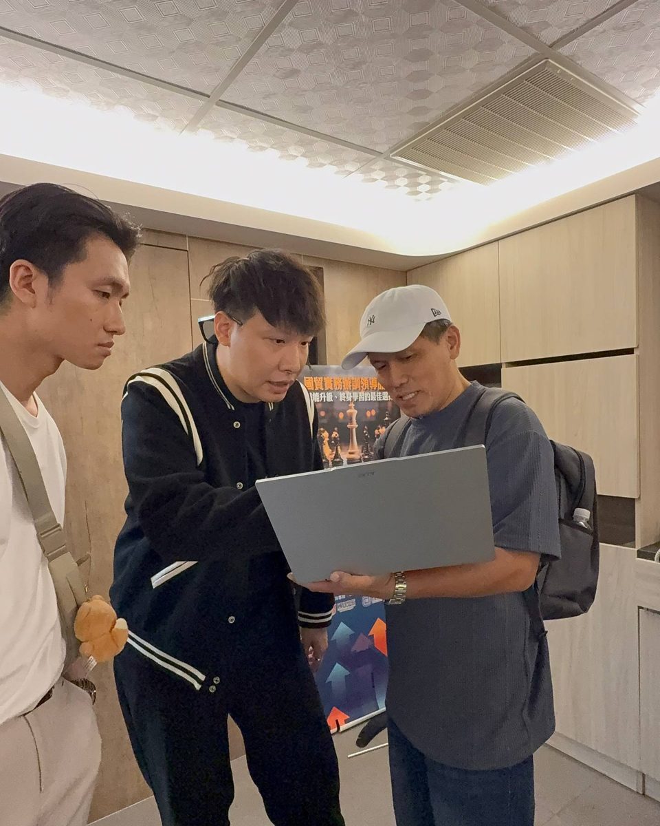 Jay 拿著筆電，一對一帶一位戴帽子的學員看盤面